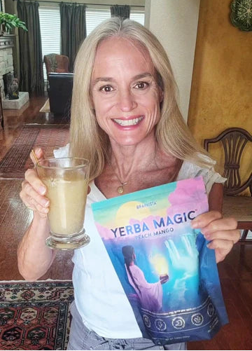 Woman holding a glass of liquid and a 'Yerba Magic' package indoors.