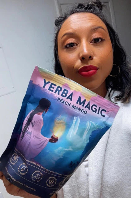 Person holding a package labeled 'Yerba Magica' against a white wall.